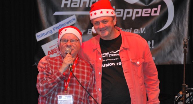 Joachim und Peter mit Weihnachtmannmützen live auf der Bühne beim Moderieren