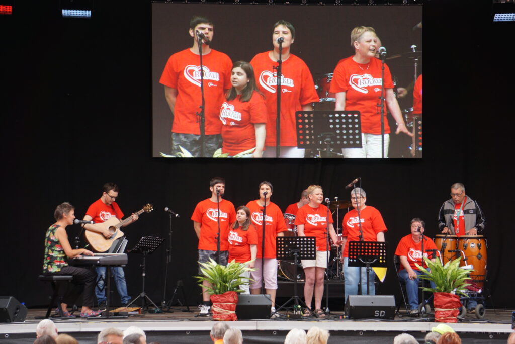 10 Mitglieder der Band Herzrocker live auf der Bühne, 9 davon mit gleichem roten T-Shirt.