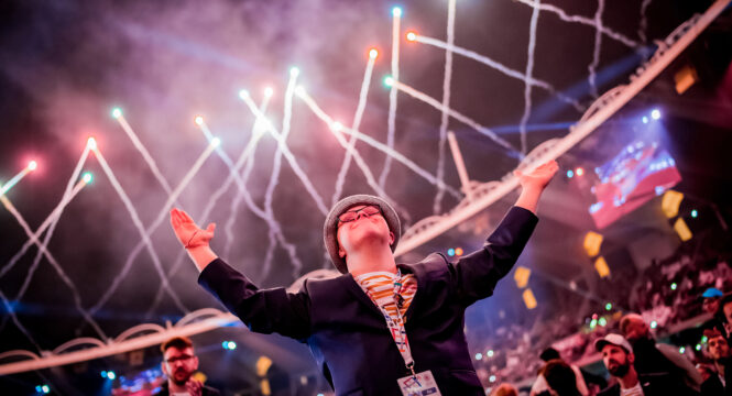 Junger Mann glücklich in einem voll besetzten Stadion mit Feuerwerk darüber