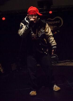 Rapper Artur live auf der Bühne mit Mikro und roter kappe