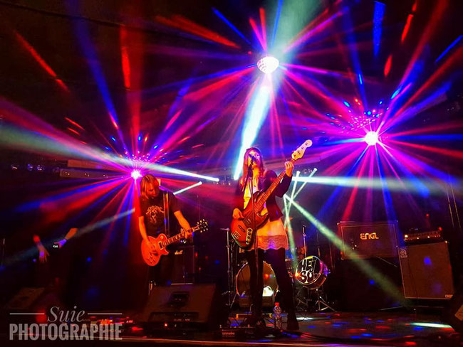 Zwei Musiker:innen mit Gitarre und E-Bass live auf der Bühne mit roter Bühnenbeleuchtung