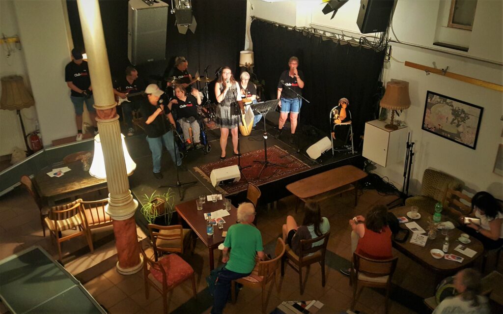 Die Band ClubRock auf der Bühne in einem sed hr schönem alten Saal mit Säulen. Das Foto ist              von oben aufgenommen und man sieht das Publikum an Tischen sitzen.