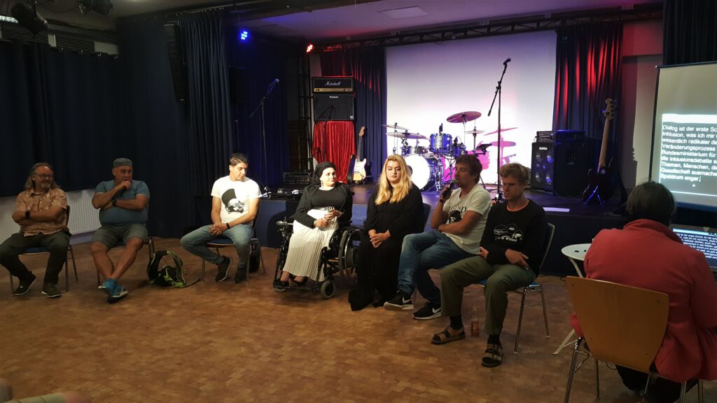 Gesprächsrunde im Brakula in Hamburg. Im Bild Sebastian im Gespräch mit 6 weiteren Personen, Mischa Gohlke von Grenzen sind relativ spricht in ein Mikrofon.