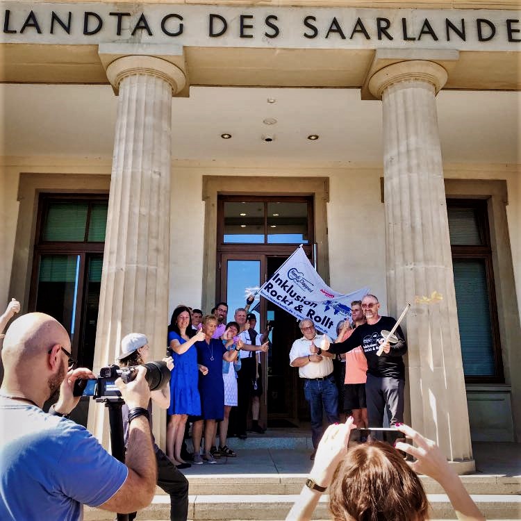 Sven Marx und Sebastian Marx bei der Übergabe der Forderungsliste vor dem Landtag des Saarlandes. Sie stehen vor dem Eingang, links und rechts zwei griechische Säulen des Gebäudes.