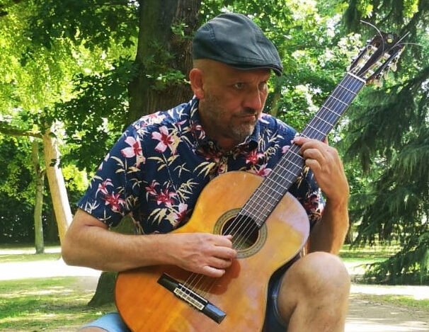 Ein Mann sitzend auf einer Akustikgitarre spielend