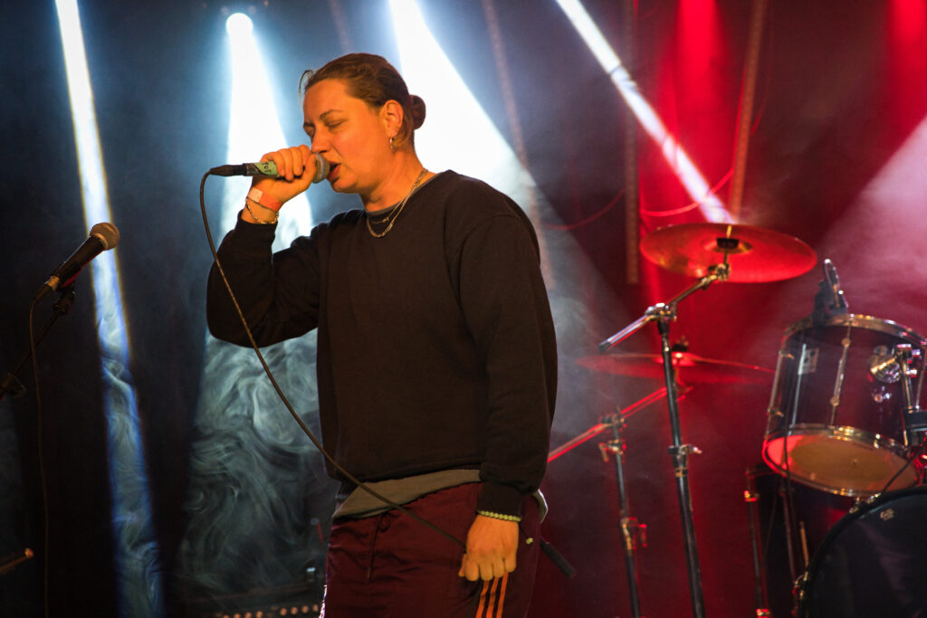 Rapperin Lena Stoehrfaktor auf der Bühne, ein Micro in der Hand. Hinter ihr weißes und rotes Bühnenlicht