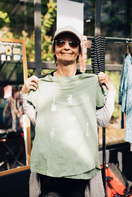eine Frau hält ein von ihr gestaltetes T-Shirt in die Kamera.