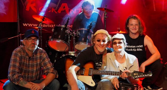 Buntfoto von den fünf Mitgliedern der Band auf einer Bühne sitzend - alle gut gelaunt