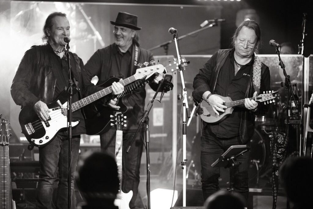 (Auf dem Bild sind drei Musiker um die 50 von der Band Ossternhagen zu sehen, ausgerüstet mit Bassgitarre, Akustikgitarre und Mandoline