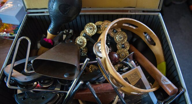 ein geöffneter Koffer mit vielen Percussionsinstrumenten, wie zb Kuhglocke, Schellenkranz , Rasseln