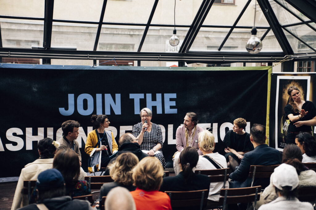 3 Frauen und 2 Männer sitzen auf der Bühne in einer Podiumsgespräch. Rechts im Bild eine Gebärdendolmetscherin
