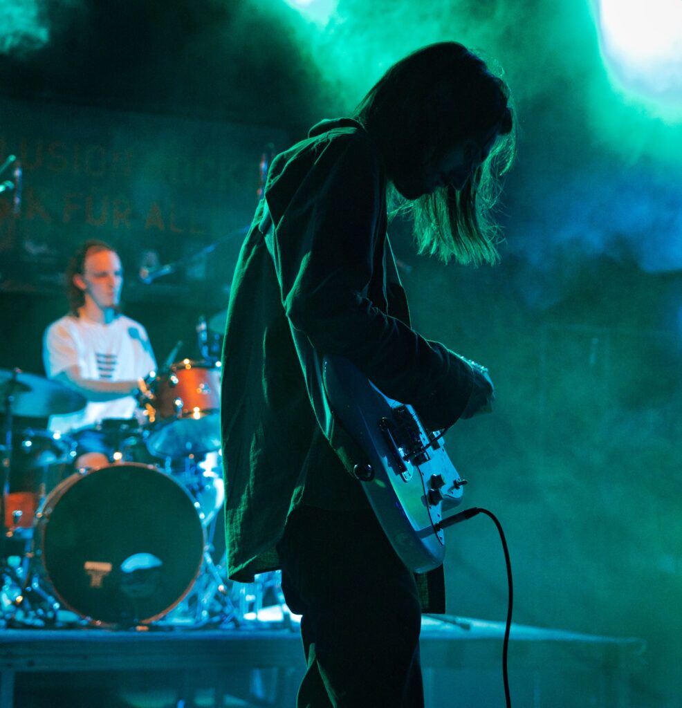 ein Gitarrist von der Seite im grünen Gegenlicht eines Bühnenscheinwerfers, viel Bühnennebel, ... ein "Rock`nRoll-Foto" 