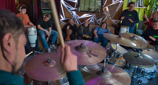 man sieht einen Schlagzeuger vovon hinten am Schlagzeug und davor mehrere Workshopteilnehmer mit verschiedenen Trommeln
