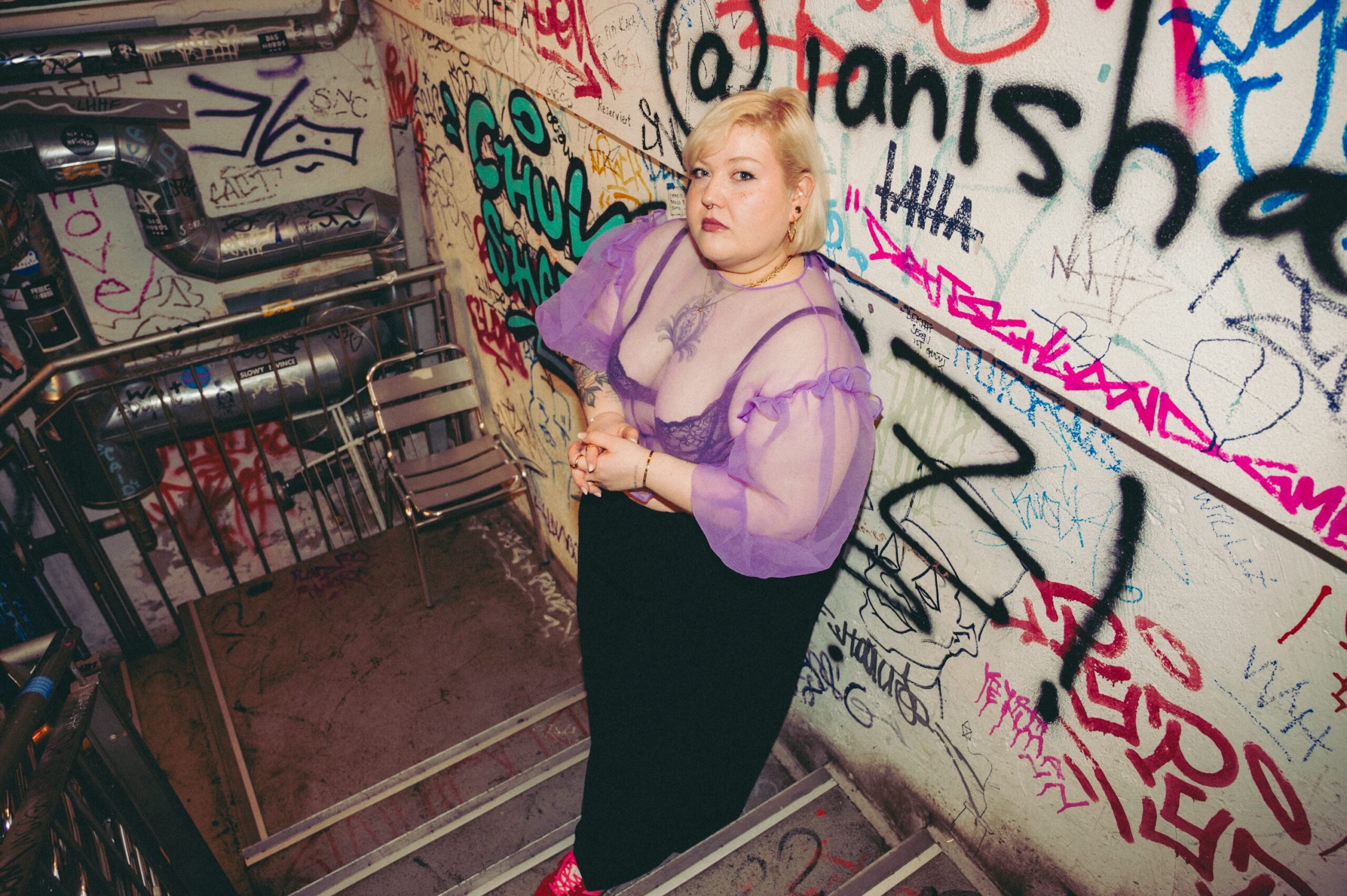 Foto von einer Frau in einem Treppenhaus voller Graffiti, 